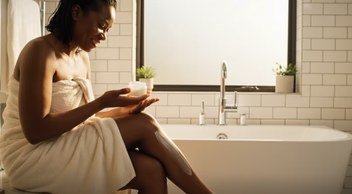 Woman applying body lotion after a bath